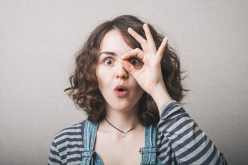 Young happy woman holding her hands over her eyes as glasses and  looking through fingers