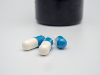 blue and white pills on a white background. self-therapy during coronavirus. close up