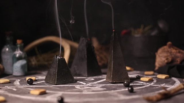 Black magic candles burn and go out from a gust of wind. Smoke on the background of the magical attributes of black art. Halloween concept.