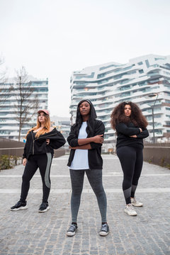 Three sportive young women posing in the city