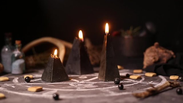 Black magic candles burn and go out from a gust of wind. Smoke on the background of the magical attributes of black art. Halloween concept.