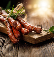 Kabanosy, polish sausages made of pork on a board with addition of fresh herbs and spices on a...