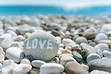 Fototapeta na wymiar stones on the beach with a blue sea and the inscription love
