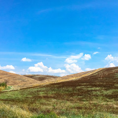 Summer landscape of Italian hills with blue sky and clouds.