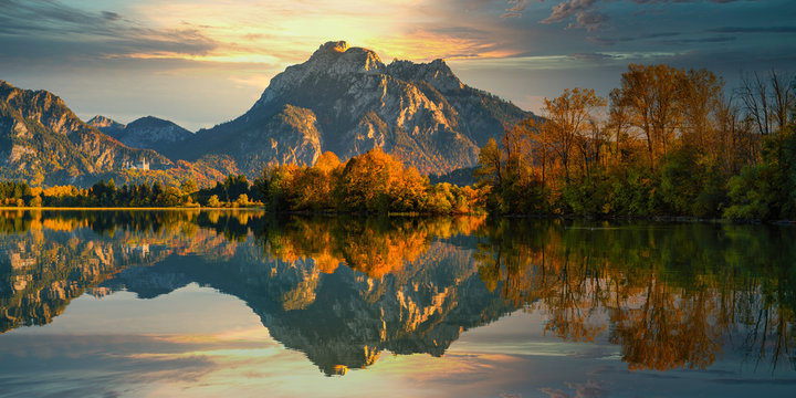 Germany, Bavaria, Hohenschwangau,?Forggensee?lake reflecting surrounding trees and hills at autumn dusk