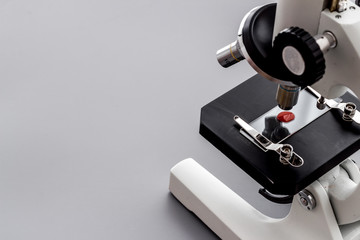 Research with microscope. Laboratory backround with blood sample on grey table copy space