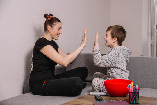 Happy And Funny Mom With Her Son Are Clapping Hands Sitting At Home On Isolation