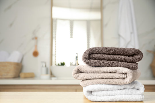 Fresh towels on wooden table in bathroom. Space for text