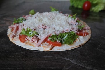 homemade pizza on a dark background cheese lettuce and tomatoes close up