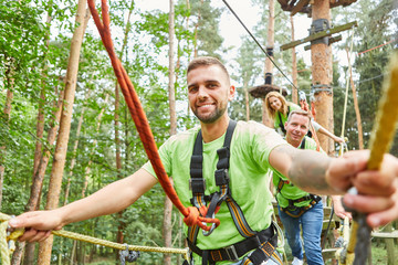 Man and his team climbing in the high ropes course - obrazy, fototapety, plakaty