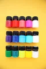 colorful paint in small jars on a yellow background bright background beautiful screensaver