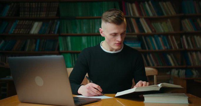 The guy is reading a book and makes notes in the librery. Education in the library. 4K