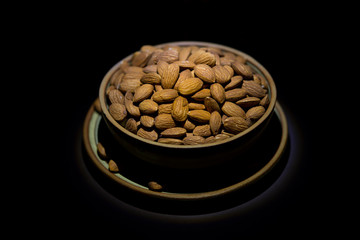 Natural fresh almonds in a wooden pot on black spotlight