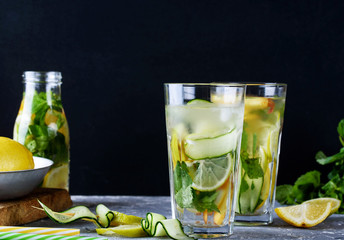 Refreshing fruit drinks with lemon, mint, peach in glass bottles and tubes on the table.