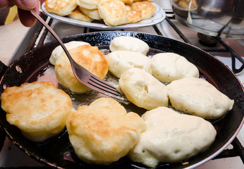 Turn over the fritters with a fork in a hot pan. fritters cooking concept. Delicious, homemade fritters.