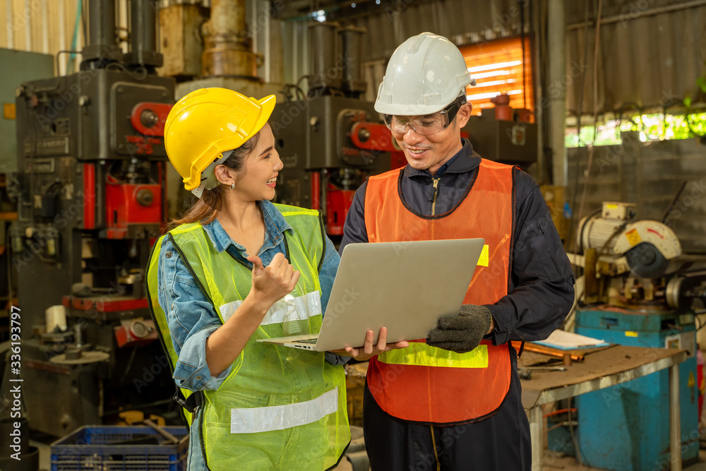 Poster two engineer in hard hat wearing safety using laptop for planning a project at factory site.