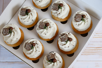 White box with cake with cream, decorated with pieces of chocolate waffle.