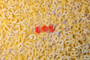 Morse code S.O.S. word with alphabet letters soup pasta. Aid concept.