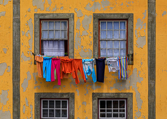 Colorful facade of a traditional house with peeling paint in the Ribeira with laundry hanging outside, Porto, Portugal