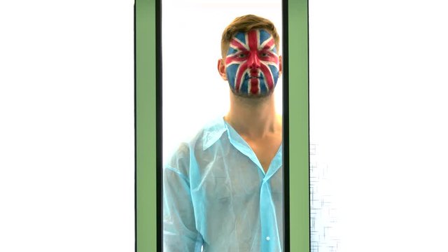 Corona Virus Lockdown. Sad male medical patient with a painted UK flag on his face. Pandemic, epidemic, coronavirus. The man on a white background. Sad, sick fan of the football team. Union Flag.
