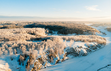 Aerial view of the winter snow covered forest and frozen river from above captured with a drone