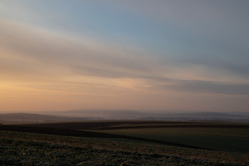 Wiosenny krajobraz pól o poranku  ze wzgórzami w tle