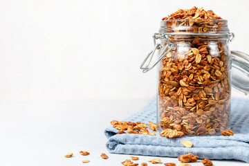 Oatmeal granola cereal in open glass jar on white background
