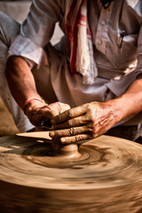 Pottery - skilled wet hands of potter shaping the clay on potter wheel. Pot, vase throwing. Manufacturing traditional handicraft Indian bowl, jar, pot, jug. Shilpagram, Udaipur, Rajasthan, India