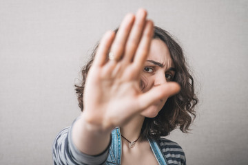 A woman shows a gesture stop. On a gray background.