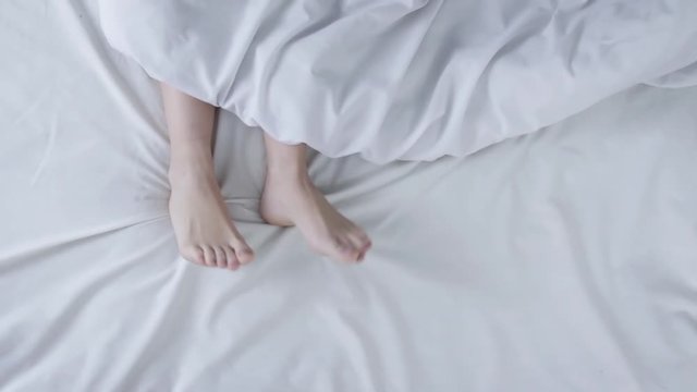Female legs feet lying in bed, top view, morning waking up and relaxing. Lifestile concept