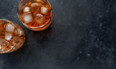Two glasses with whiskey on a stone background with copy space for your text.