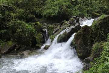 Beautiful landscape of cascade falls over mossy rocks, stones cover with moss, in a Mountain in Sichuan, China