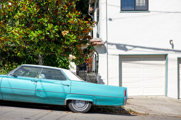 A classic blue sedan parked on a sloped street