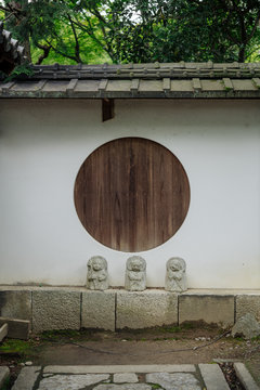 Jizos Standing in front of Japanese Wall