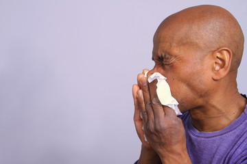 COVID-19 Coronavirus  pandemic outbreak man blowing his nose fighting the disease with grey background stock photo