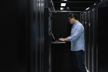 Server room technician using computer in server room