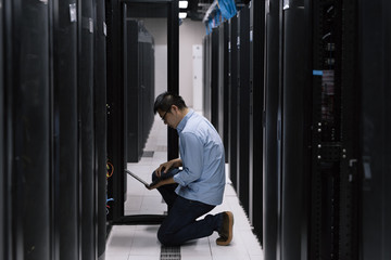 Server room technician using computer in server room