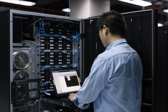 Server room technician using computer in server room