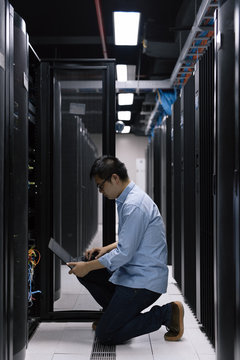 Server room technician using computer in server room