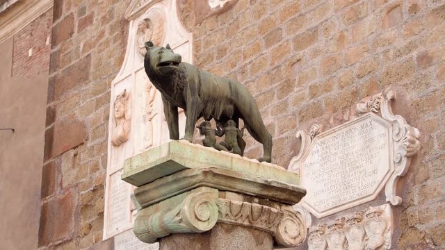 Statue of she-wolf on Capitoline hill against red brick wall. Twins founders of Rome city - Romulus and Remus - suckling she-wolf. Icon of Italian capital Rome city
