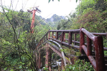 Fototapeta premium wooden bridge across a waterfall river in a mountain forest in Sichuan, China
