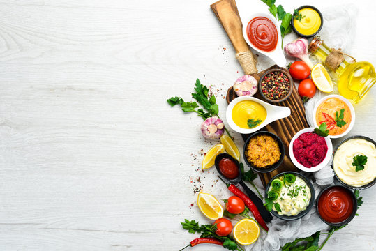 Set of sauces and spices on white wooden background. Top view.