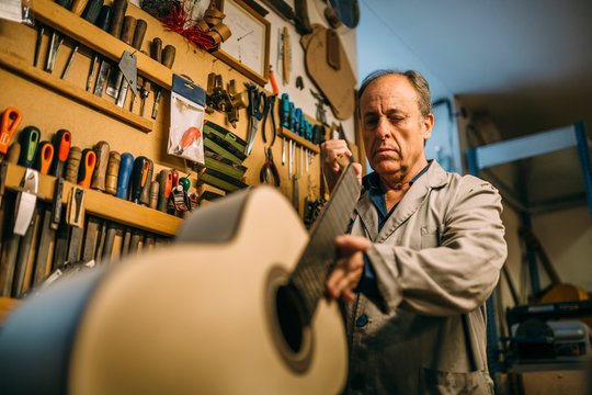 Senior luthier checking the finishing of a handcrafted spanish guitar