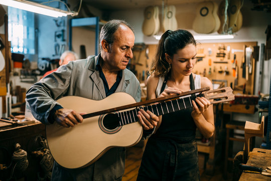 Luthiers checking the finishing of a custom spanish guitar
