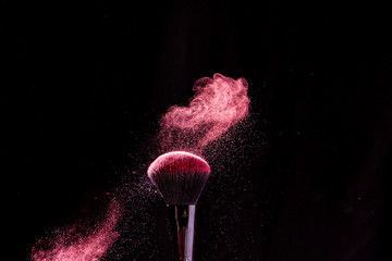 Colorful explosion on makeup brushes on a black background