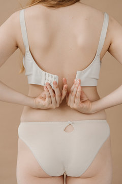 Female fasten bra by hands, pulling to center to parts.