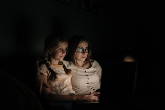 Mother and Daughter working with laptop at night at home.