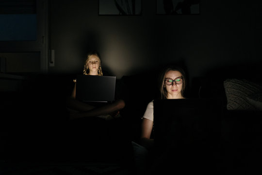 Mother and Daughter working with laptop at night at home.