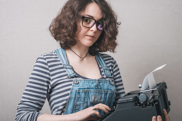 Young attractive secretary writing with an old typewriter. Conceptual image.