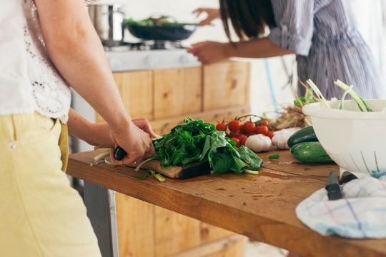 Two female friends cooking lunch together